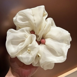 Close-up of white organza scrunchie featuring delicate floral embroidery and sheer texture