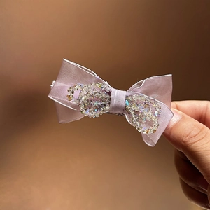 Close-up of pink crystal bow hair claw clip showing intricate beadwork and silk texture