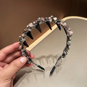 Detail of handmade crystal headband with multi-color stones and black spike accents