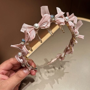 Detailansicht eines rosa Satin-Haarreifs mit Perlen, Strasssteinen und integrierten Clips