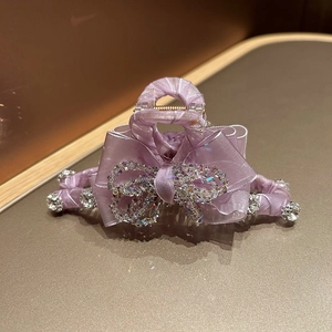 Detail of a premium purple ribbon hair claw clip with sparkling rhinestones and metal spring