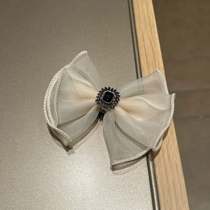 Detailed macro view of an organza bow hair clip with a rhinestone-encrusted black gem center