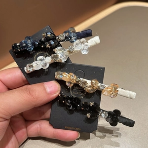 Set of four handmade crystal hair clips with fabric trim shown on a display card