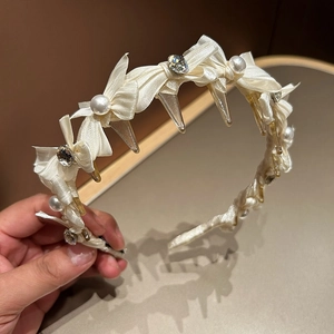 Details des cremefarbenen Satin-Haarreifens mit eleganten Perlen und Strass-Verzierungen