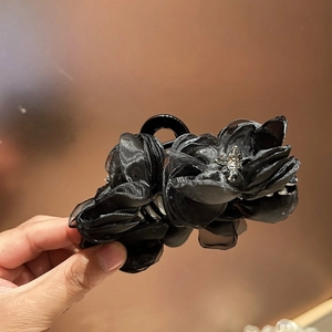 Dettaglio della molletta per capelli in organza nera con accento centrale di diamanti