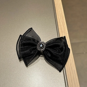 Detail of black organza bow hair clip with luxury rhinestone center and mesh texture