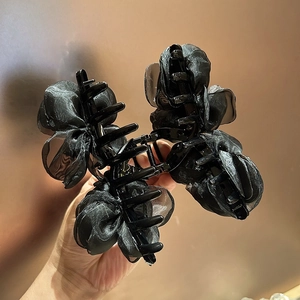 Dettaglio di un grande fermaglio per capelli con fiori in organza nera e petali 3D in rete