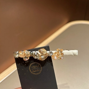 Detail of handmade amber crystal hair clip with beads on a branded display card