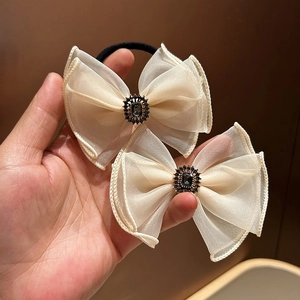 Close-up of off-white organza bow hair tie with grey gemstone and crystal center