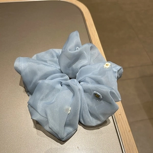 Detail of light blue organza scrunchie featuring delicate white daisy embroidery