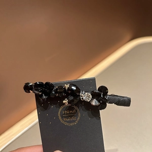 Detailed shot of handmade black crystal hair clip with sparkling rhinestones on card