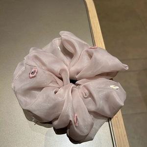 Detail of light pink organza scrunchie with delicate floral embroidery and pearly sheen