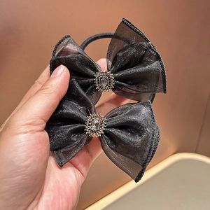 Detailed macro view of black organza bow hair clip with sparkling rhinestone centerpiece