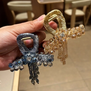 Close-up of luxury crystal hair claws with elegant beaded tassels in blue and champagne