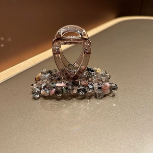 Détail d'une pince à cheveux artisanale ornée de cristaux colorés et de strass gris fumé