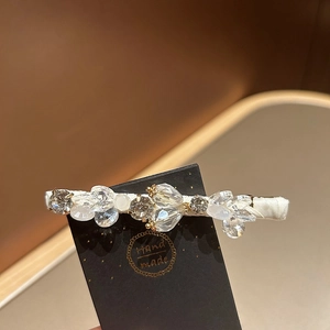 Close-up of handmade crystal hair clip with sparkling rhinestones on white textile base