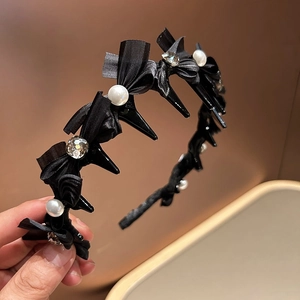 Detail eines schwarzen Schleifen-Stirnbands mit weißen Perlen, Kristallen und Haarclips