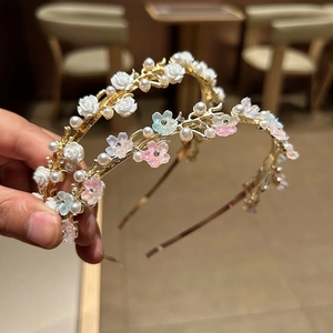 Detail of delicate pearl headband with embossed roses and cherry blossoms on gold alloy