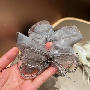 Detailed shot of light grey mesh scrunchie with bow and transparent crystal beads