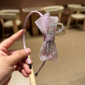 Detailed shot of a purple satin hair clip with crystal-embellished ribbon bow