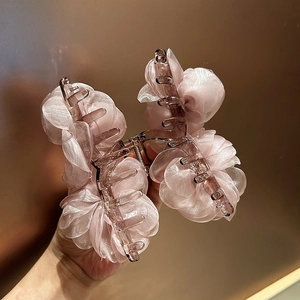 Dettaglio dei petali in tessuto rosa traslucido su una grande pinza per capelli a fiori 3D