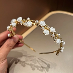 Detail view of gold headband with resin roses, pearls and rhinestones on a warm background