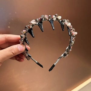 Detail of handmade headband with pink crystals, natural stones, and black inner teeth