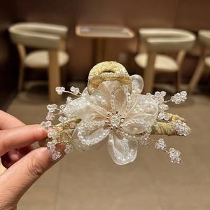 Dettaglio della grande molletta dorata con fiore di organza e perline di cristallo