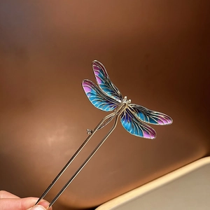Dettaglio di forcina a libellula con ali sfumate blu-viola e perno a U in metallo dorato