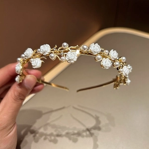 Detail of white resin rose headband with pearls and rhinestones on gold frame