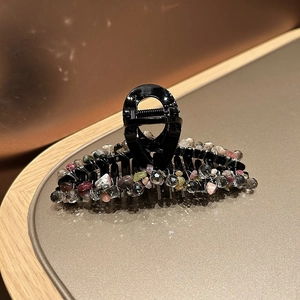 Détail d'une pince à cheveux avec perles de cristal colorées et pierres sur base noire