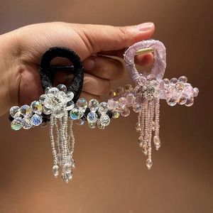 Detail view of satin hair claws with luxury crystal flowers and long sparkling tassels