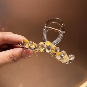 Détail d'une pince à cheveux en acrylique avec pierres jaunes et perles de cristal