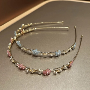 Détail de serre-têtes en métal avec fleurs en résine colorées et perles blanches