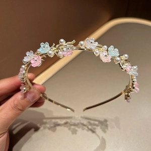 Detail of slim gold headband with faux pearls and delicate resin flowers with crystals