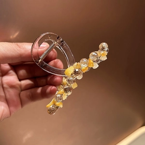 Détail d'une pince à cheveux transparente ornée de pierres jaunes et perles cristallines