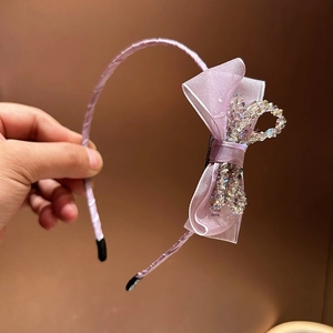 Close-up of a purple mesh bow headband with sparkling crystals and a satin finish