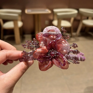 Dettaglio del fermaglio per capelli a fiore in organza con perle e cristalli rossi