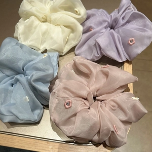 Detailed macro view of organza scrunchies with delicate floral embroidery in pastel colors