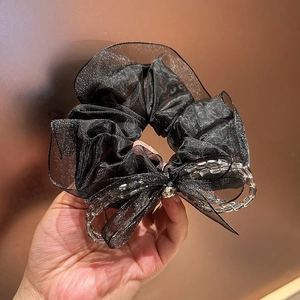 Detail of black lace hair scrunchie with crystal bow and transparent bead accents