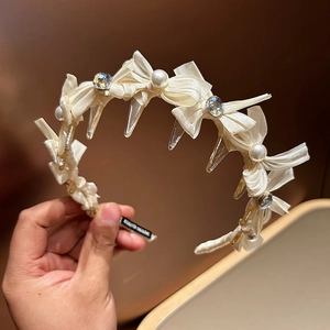 Detail eines handgefertigten weißen Satin-Haarreifens mit Perlen und Kristallen am Kamm