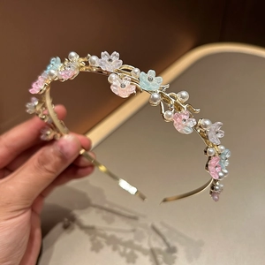 Detail of a thin gold headband with pastel resin flowers, faux pearls and crystals