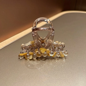 Détail d'une pince à cheveux en résine ambrée avec pierres jaunes et perles en cristal