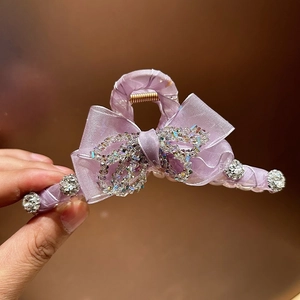 Close-up of elegant purple bow hair claw clip with colorful rhinestones and tulle detail
