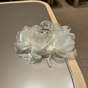 Dettaglio del fermaglio a fiore in organza bianca con strass e base trasparente