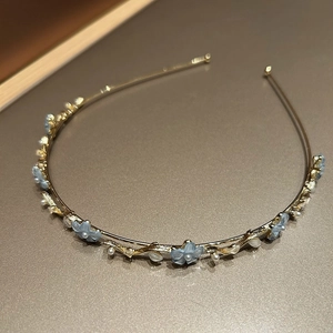 Détail d'un élégant serre-tête doré avec fleurs bleues et perles pour femmes chic