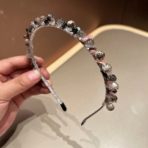 Macro detail of handmade beaded headband with faceted crystals and pink stone accents