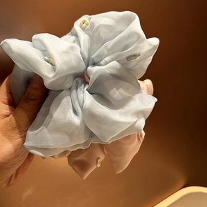 Detail of light blue and pink organza scrunchies with white daisy embroidery patterns