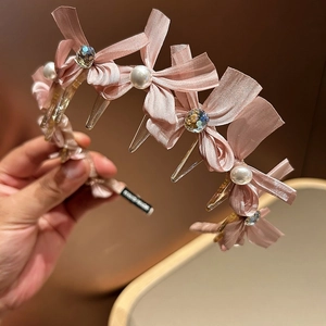 Detail eines rosa Seidenbogen-Haarbands mit Perlen, Kristallen und handgemachtem Etikett