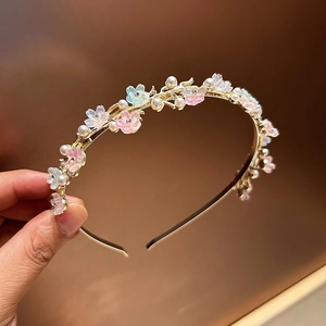 Detail of gold metal headband with pink and blue resin flowers and white pearls